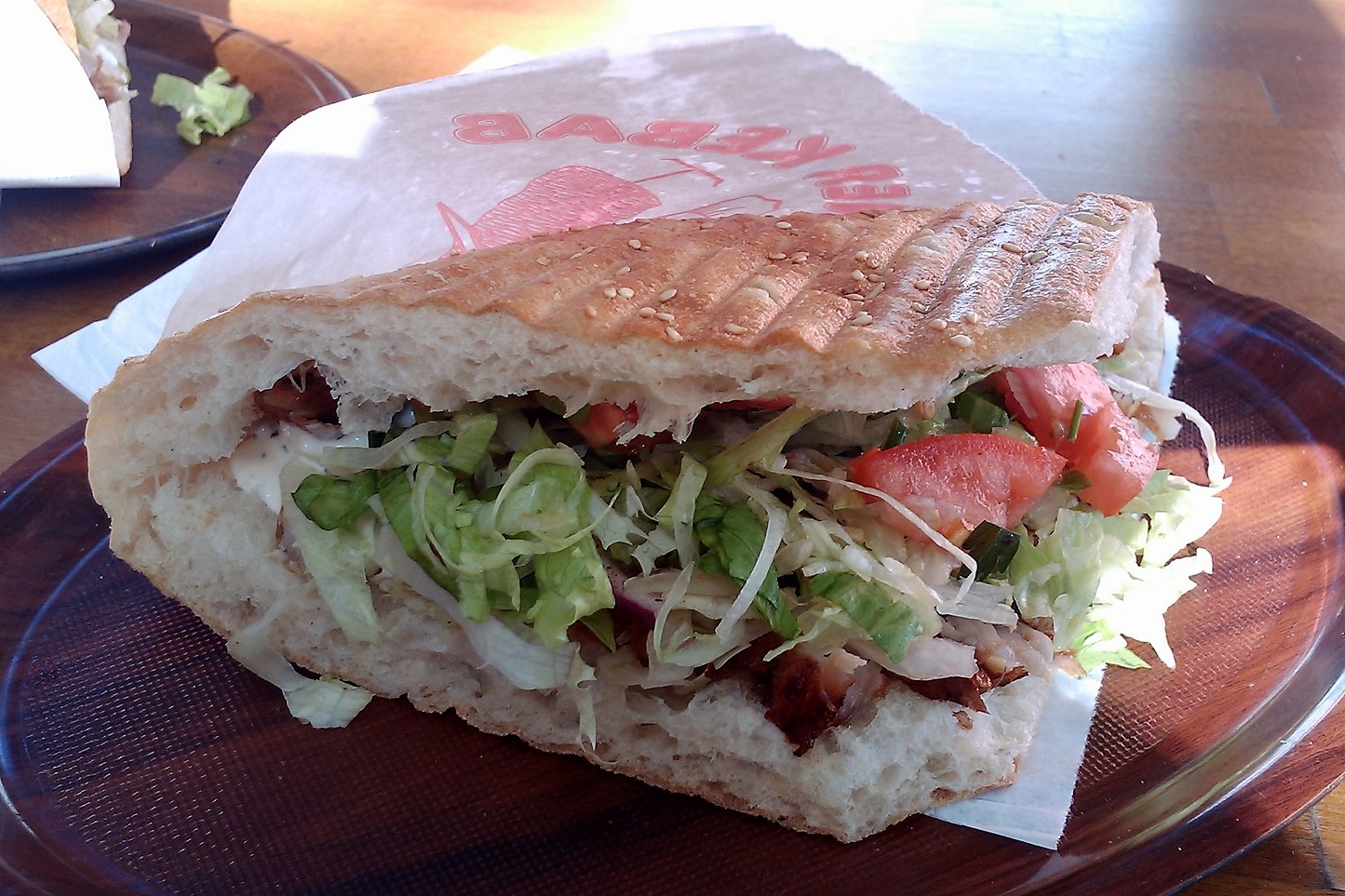 Kebab w opiekanej bułce z sałatą, pomidorem i sosem